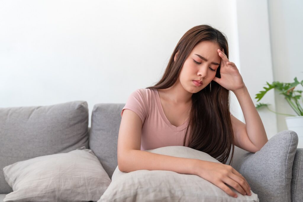 Asian young woman holding her head,she has a headache sitting on