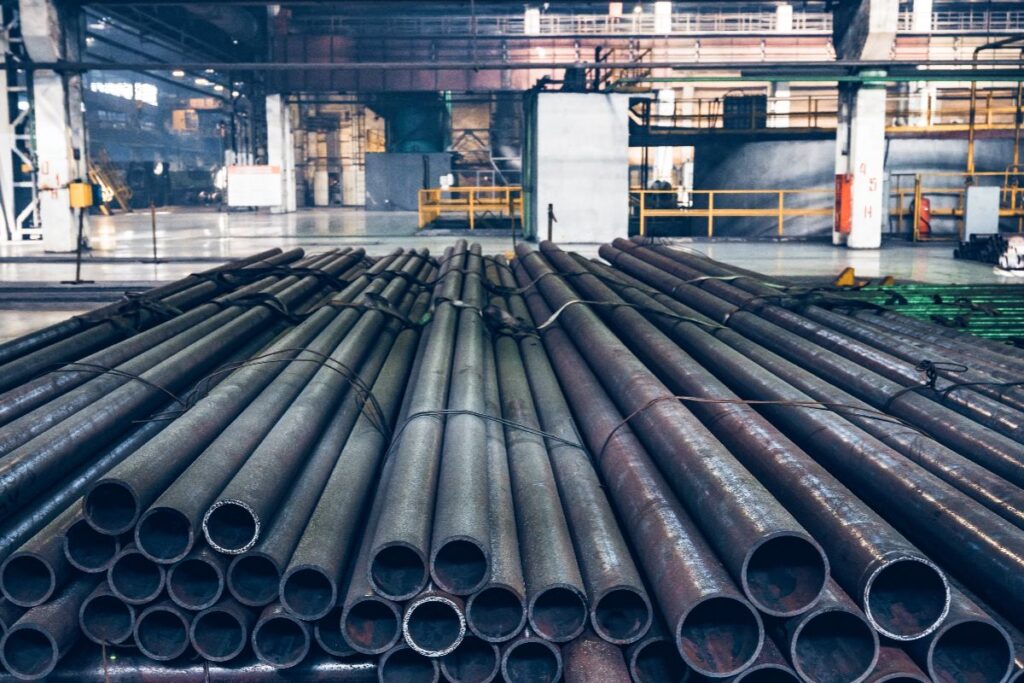 Black iron pipes stacked inside an industrial warehouse