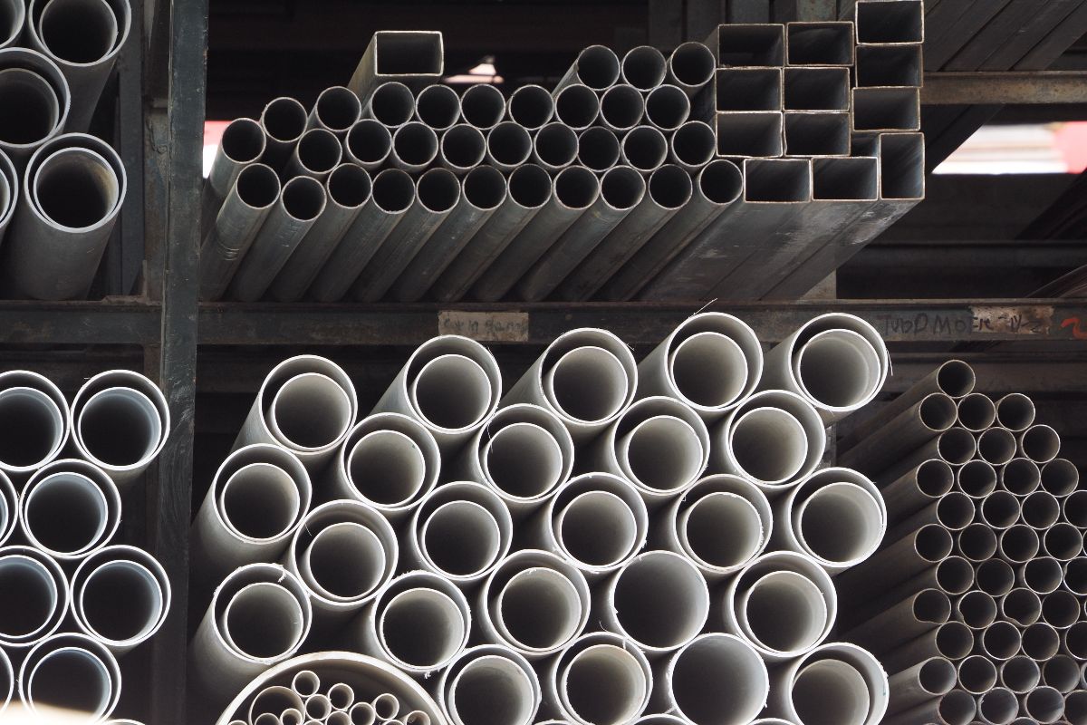 Stacked round and square steel pipes stored in a warehouse for construction and industrial supply
