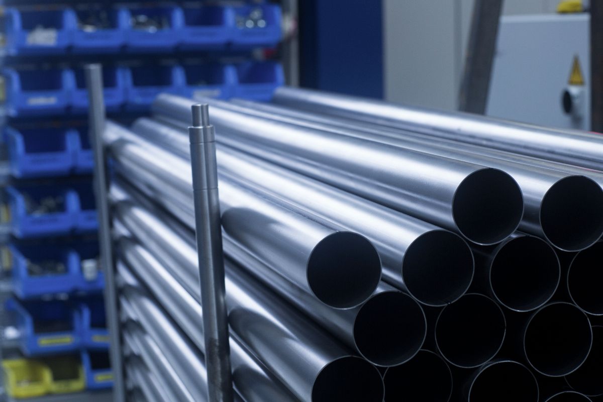 Smooth galvanized iron pipes stacked indoors, showing uniform finish and round openings