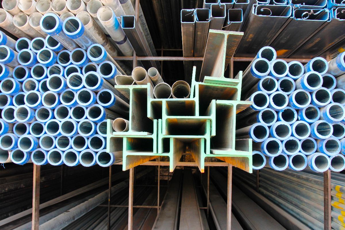 Steel pipes and structural sections arranged in warehouse racks for construction supply