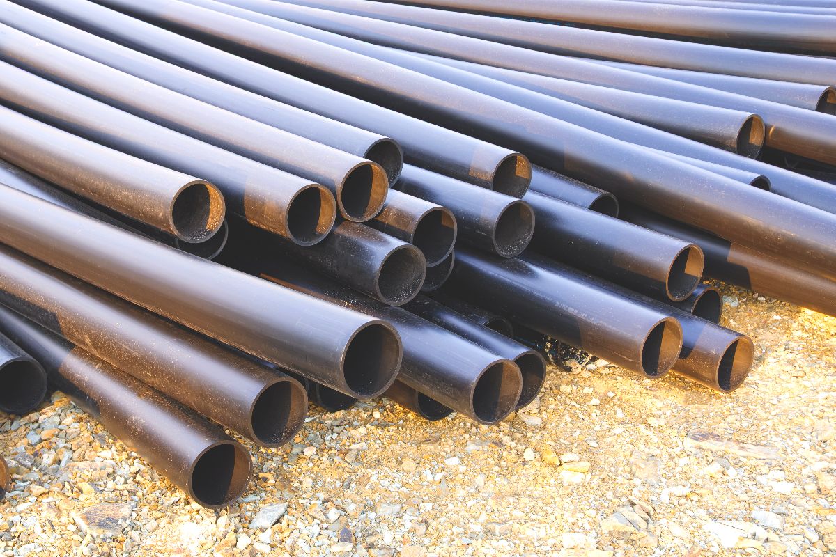 Black iron pipes stacked outdoors, showing round pipe openings and durable steel surfaces