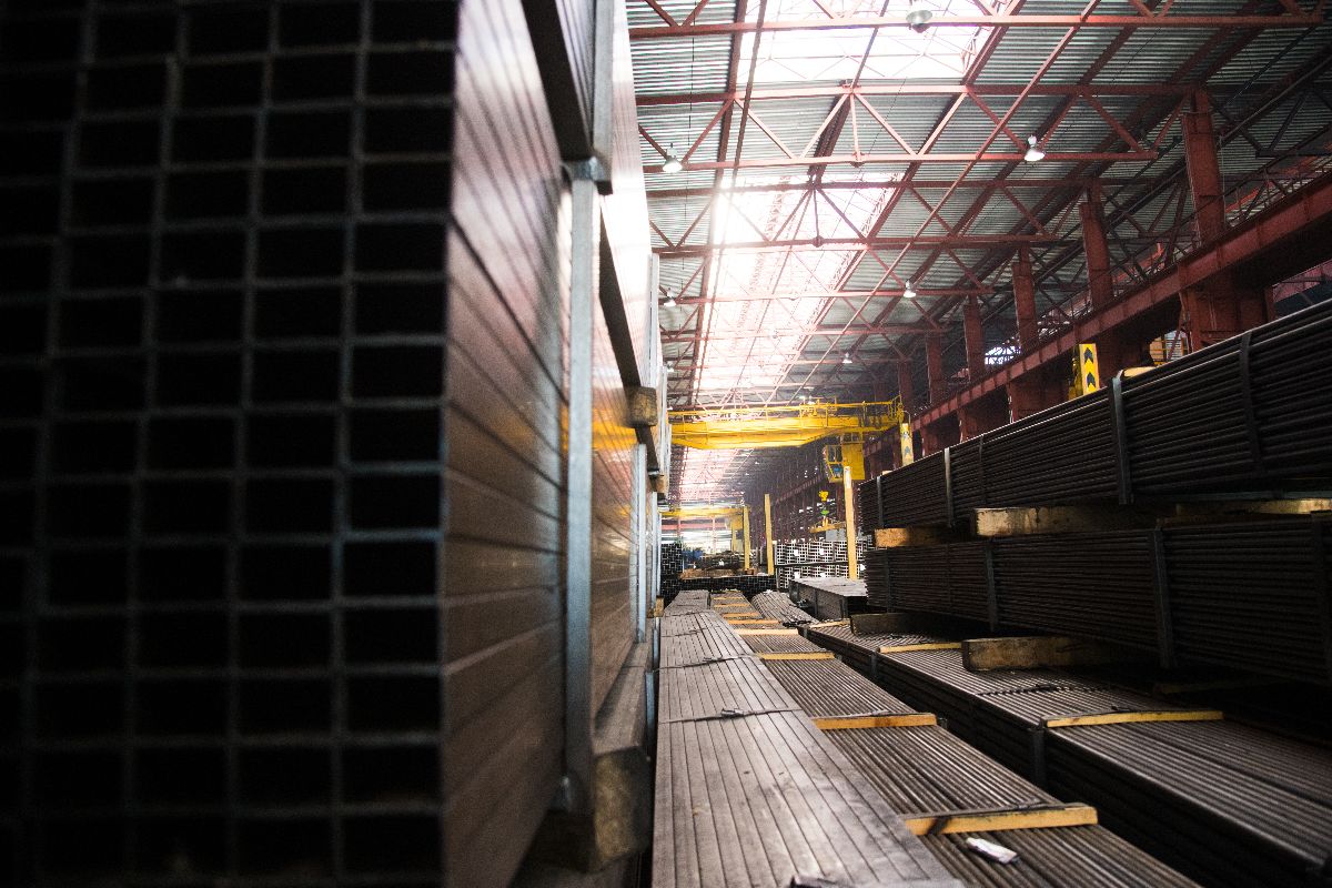 Black iron pipes and square tubes stored inside an industrial warehouse for construction supply