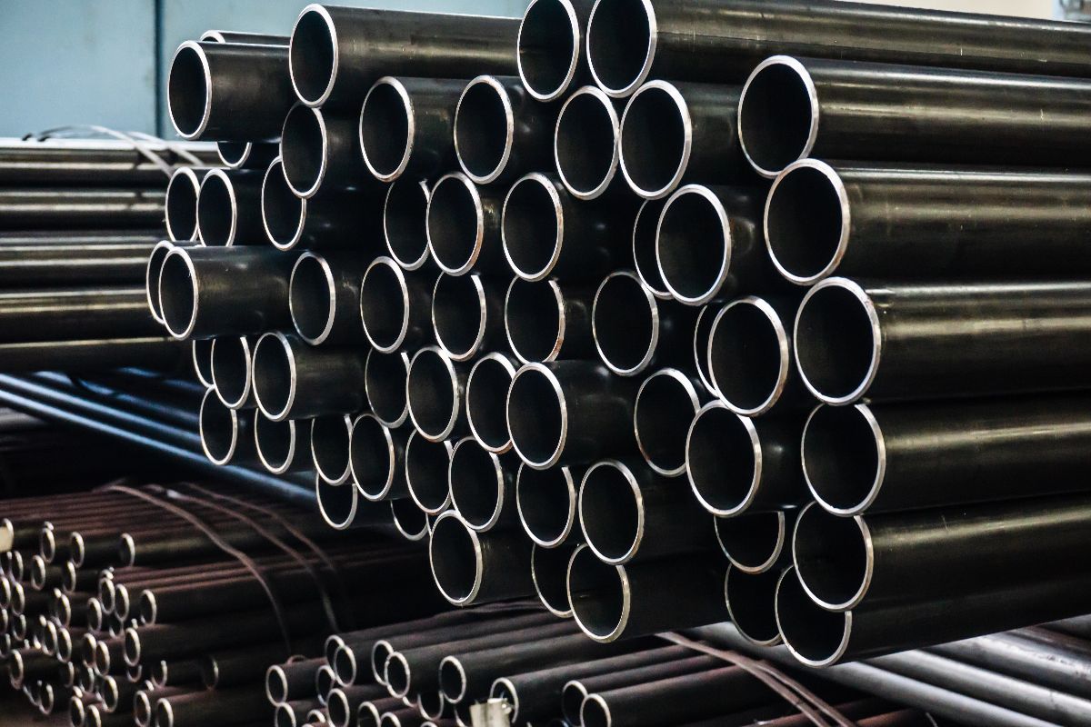 Black galvanized pipes stacked in a warehouse, showing round openings and consistent pipe dimensions